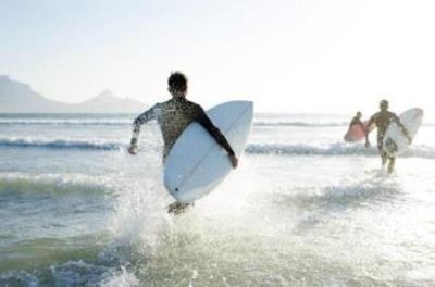 Young surfers running into the ocean with surf boards in their hands.