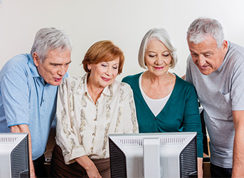 Vier Senioren betrachten einen PC