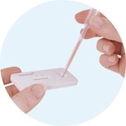 Close-up of two fingers holding a pipette with diluent that is dropped into a test cassette