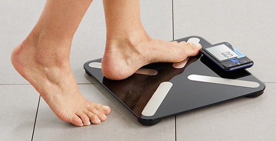 A person is standing with one foot on a Veroval scale