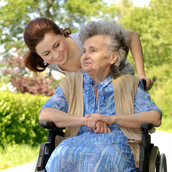 Frau schiebt Seniorin im Rollstuhl