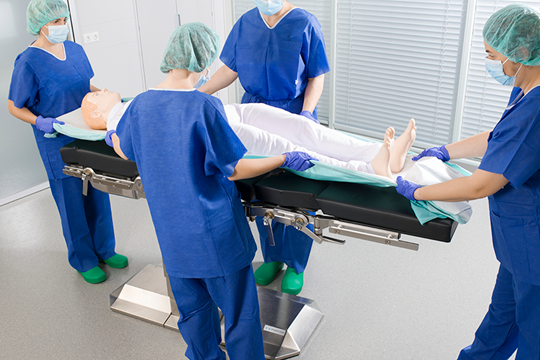 Patient mit Foliodrape wird vom OP-Tisch gehoben