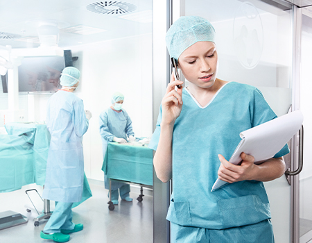 Enfermera quirúrgica hablando por teléfono frente un quirófano - HARTMANN