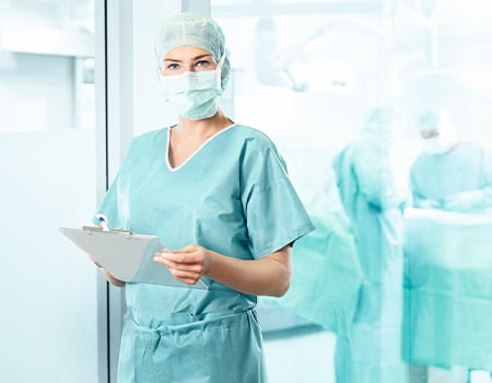 Enfermera quirúrgica mirando a cámara con una lista de intervenciones en la mano - HARTMANN
